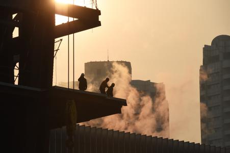 © Greg Baker/AFP/Getty Images. Construction workers stand on the structure of a building in Beijing on Dec. 18, 2014. Experts say that a predicted slowdown in the country's economic growth represents a period of structural change that will secure long-term stability.