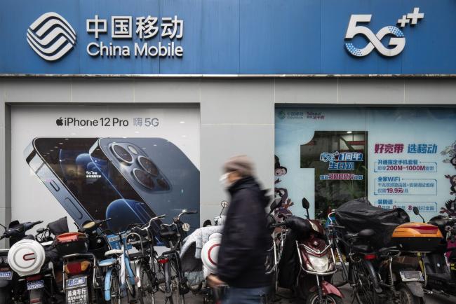 © Bloomberg. A pedestrian walks past a China Mobile Ltd. store in Shanghai, China, on Wednesday, Jan. 6, 2021. The New York Stock Exchange is considering reversing course a second time to delist three major Chinese telecommunications firms after conferring further with senior authorities on how to interpret an executive order President Donald Trump issued Nov. 12, according to people familiar with the matter.