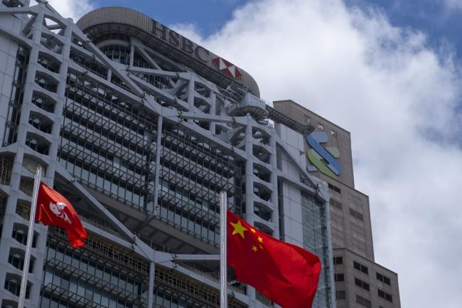 © Bloomberg. The flags of China and the Hong Kong Special Administrative Region (HKSAR) fly near the HSBC Holdings Plc building, left, and the Standard Chartered Plc building in Hong Kong, China, on Thursday, June 4, 2020. HSBC and Standard Chartered, the two British institutions that dominate Hong Kong's banking system, backed Beijing in the standoff over a proposed new security law, joining Jardine Matheson Holdings Ltd. and some of the city's biggest developers in wading into the political minefield of the former colony's future.