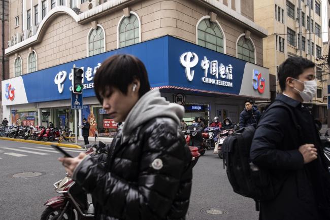 © Bloomberg. Pedestrians walk past a China Telecom Corp. store in Shanghai, China, on Wednesday, Jan. 6, 2021. The New York Stock Exchange is considering reversing course a second time to delist three major Chinese telecommunications firms after conferring further with senior authorities on how to interpret an executive order President Donald Trump issued Nov. 12, according to people familiar with the matter.