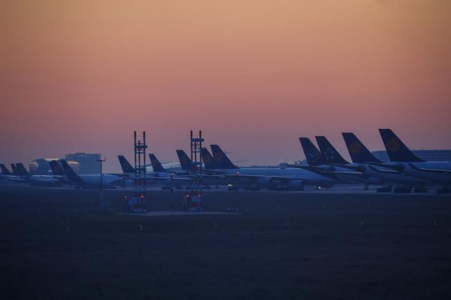 © Bloomberg. Passenger aircraft, operated by Deutsche Lufthansa AG, sit grounded on the closed north west runway at Frankfurt Airport, operated by Fraport AG, at dawn in Frankfurt, Germany, on Thursday, March 26, 2020. Unable to fill planes with passengers as the coronavirus destroys travel demand, airlines are instead using their fleets to transport more cargo, including medicines, smartphones and Korean strawberries. Photographer: Bloomberg/Bloomberg