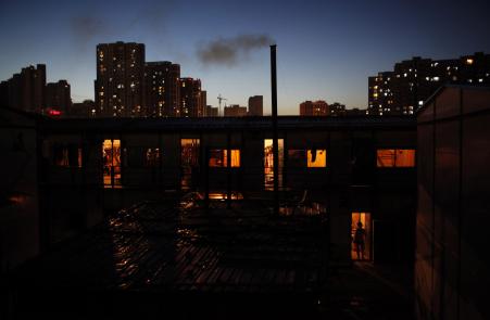 © Reuters/Aly Song. A female migrant construction worker walks into her dormitory near newly-built residential apartments in Shanghai on Aug. 12, 2013.