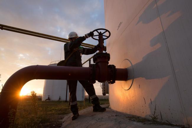 © Bloomberg. An employee turns a control valve on pipework beside a storage tank at an oil delivery point operated by Bashneft PAO in Sergeevka village, near Ufa, Russia, on Monday, Sept. 26, 2016. Bashneft distributes petroleum products and petrochemicals around the world and in Russia via filling stations. Photographer: Andrey Rudakov/Bloomberg