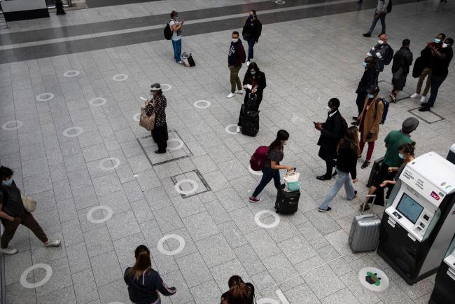 © Bloomberg. Travelers walk over social distancing floor markers at Gare du Nord railway station in Paris on June 15. Photographer: Adrienne Surprenant/Bloomberg