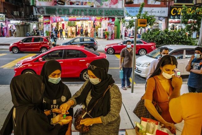 © Bloomberg. Shoppers use hand sanitizer as a vendor checks a customer's temperature outside a store during a partial lockdown imposed due to the coronavirus in Kuala Lumpur, Malaysia, on Wednesday, May 20, 2020. The Malaysian government is working to implement its 260 billion ringgit ($60 billion) stimulus package, the biggest in Southeast Asia as proportion of gross domestic product, while promising another set of measures to bolster an economy struggling with the effects of the pandemic.