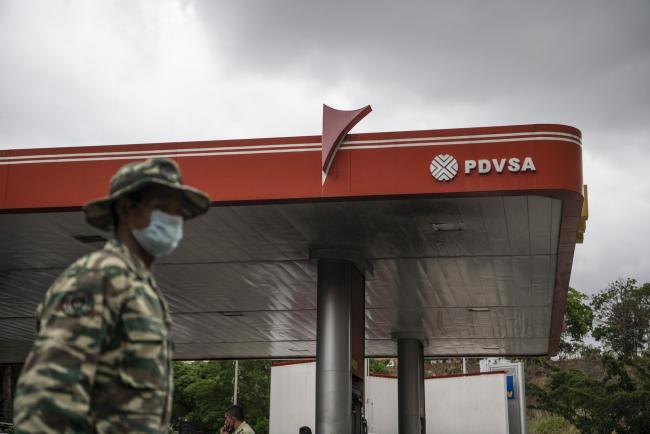 © Bloomberg. A soldier wearing a protective mask stands guard outside a Petroleos de Venezuela SA (PDVSA) gas station in Caracas, Venezuela, on Monday, June 1, 2020. Venezuela’s President Nicolas Maduro said fuel prices would increase starting in June, a historic policy shift after decades of subsidies that have allowed Venezuelans to essentially fill their tanks for free. Photographer: Carlos Becerra/Bloomberg