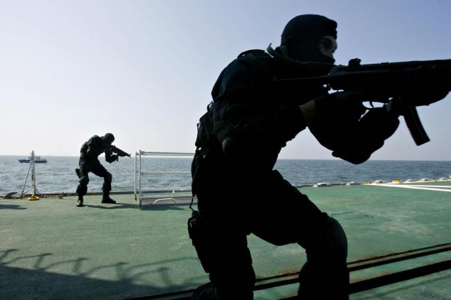 © Bloomberg. Members of the Malaysian Marine Police amphibious assault unit storm the Japanese Coast Guard ship Yashima during a joint anti-piracy exercise off the western Thailand coast near the Tarutao Islands, 02 February 2007.  Photographer: Tengku Bahar/AFP via Getty Images