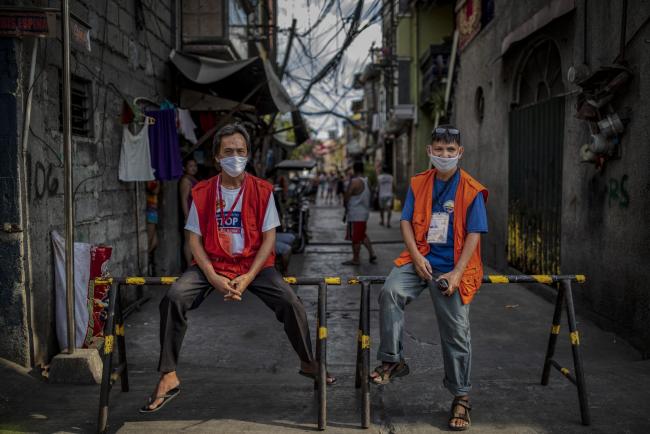 © Bloomberg. MANILA, PHILIPPINES - MARCH 20: Mauro Milan and Fernando Cabrera pose for a portrait as they guard a makeshift barricade blocking the entrance to Barangay 16 to prevent the spread of COVID-19 in their village on March 20, 2020 in Caloocan, Metro Manila, Philippines. In a bid to stop the spread of the new coronavirus, residents of Manila's poorer districts have begun putting up makeshift barricades to halt movement in its tight alleyways and jampacked slums where social distancing is nearly impossible. The Philippine island of Luzon, which includes the sprawling capital Manila, has been on lockdown since Monday as cases of the deadly virus surged. The government has made a mammoth appeal to the island's 55 million residents to quarantine themselves at home, an impossible task for many of its poorer residents who need to leave their houses daily to survive. (Photo by Ezra Acayan/Getty Images)