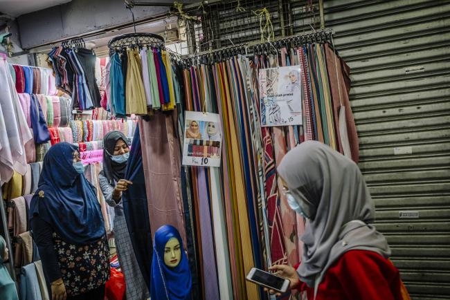 © Bloomberg. Customers wearing protective masks looks at headscarves in a store during a partial lockdown imposed due to the coronavirus in Kuala Lumpur, Malaysia, on Wednesday, May 20, 2020. The Malaysian government is working to implement its 260 billion ringgit ($60 billion) stimulus package, the biggest in Southeast Asia as proportion of gross domestic product, while promising another set of measures to bolster an economy struggling with the effects of the pandemic. Photographer: Ian Teh/Bloomberg