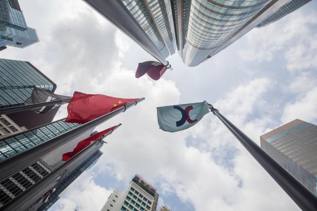 © Bloomberg. The corporate flag for Hong Kong Exchanges & Clearing Ltd. (HKEX), right, and the Chinese flag, left, fly outside the Exchange Square complex in Hong Kong, China, on Monday, Sept. 16, 2019. The Hong Kong bourse's unsolicited takeover bid for the London Stock Exchange Group Plc was greeted with a scathing rejection and the exchange suffered a further humiliation when China praised the rebuff as well. Photographer: Paul Yeung/Bloomberg