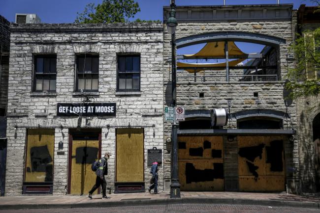 © Bloomberg. Pedestrians walk past boarded up restaurants on East Sixth Street in downtown Austin, Texas on April 13. Photographer: Bronte Wittpenn/Bloomberg