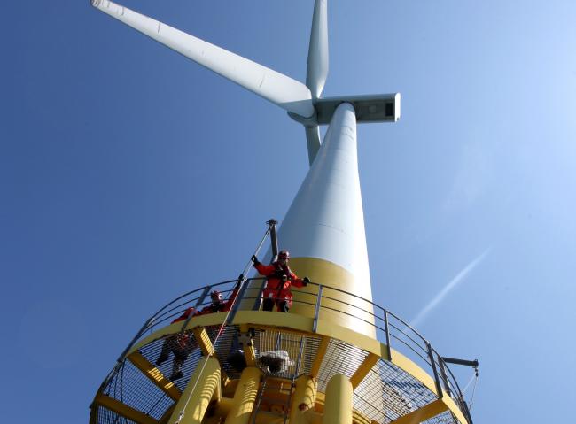 © Bloomberg. A technician raises maintenance equipment on to a wind turbine at a facility near Great Yarmouth, U.K. Photographer: Chris Ratcliffe/Bloomberg