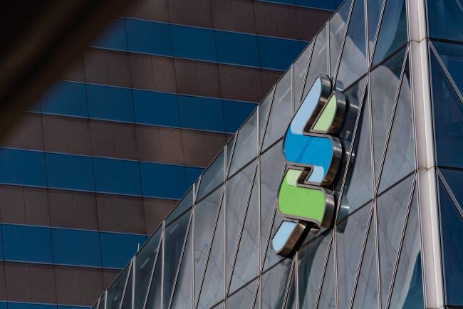 © Bloomberg. The Standard Chartered Plc logo is displayed atop the Standard Chartered Wealth Management Centre in Hong Kong, China, on Saturday, Feb 16, 2019. Standard Chartered is scheduled to release full year earnings results on Feb. 26. Photographer: Anthony Kwan/Bloomberg