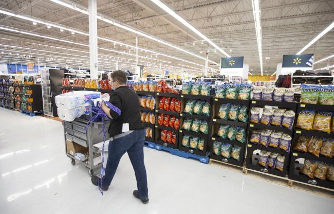 © Bloomberg. A worker wearing a protective mask walks past shelves of snack foods that are blocking access to closed aisles at a Walmart Inc. store in Montreal, Quebec, Canada, on Tuesday, Dec. 29, 2020. New Covid-19 restrictions, which are scheduled to last until Jan. 11, allow stores selling goods deemed essential to stay open while big-box stores must close off areas of their stores that contain non-essential items, the Montreal Gazette reports. Photographer: Christinne Muschi/Bloomberg