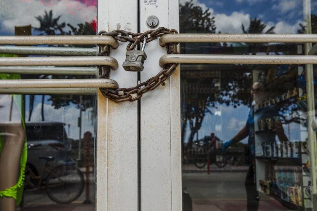 © Bloomberg. A lock and chain secure the door of a closed store in the South Beach neighborhood of Miami Beach, Florida, U.S., on Friday, March 20, 2020. Mayor Carlos Gimenez announced Wednesday that all public beaches, non-essential retail, private educational facilities, casinos and entertainment activities in Miami-Dade County will close as of Thursday night. Photographer: Scott McIntyre/Bloomberg