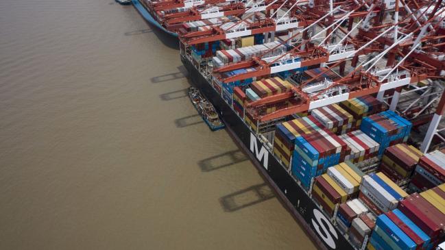 © Bloomberg. A vessel loaded with shipping containers is docked at the Yangshan Deepwater Port in this aerial photograph taken in Shanghai, China, on Sunday, July 12, 2020. U.S. President Donald Trump said Friday a phase two trade deal with China isn't under consideration, saying the relationship between Washington and Beijing has deteriorated too much. Photographer: Qilai Shen/Bloomberg