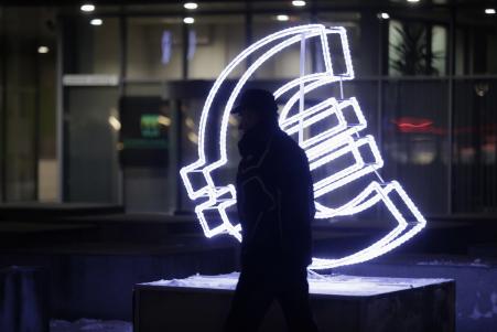 © Reuters/Ints Kalnins. A man walks past an Euro sign light installation in Vilnius, Dec. 31, 2014.