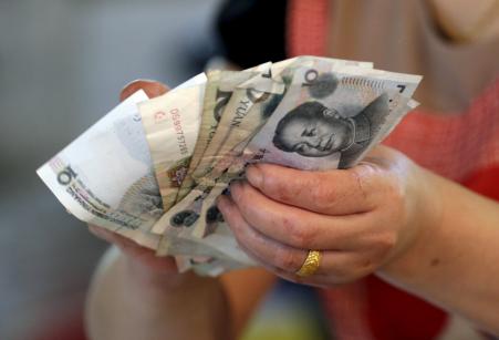 © Reuters/Jason Lee. A vendor holds Chinese Yuan notes at a market in Beijing on Aug. 12, 2015. China shocked global markets on Tuesday by devaluing its currency after a run of poor economic data, a move it billed as a free-market reform but which some experts suspect could be the beginning of a longer-term slide in the exchange rate.
