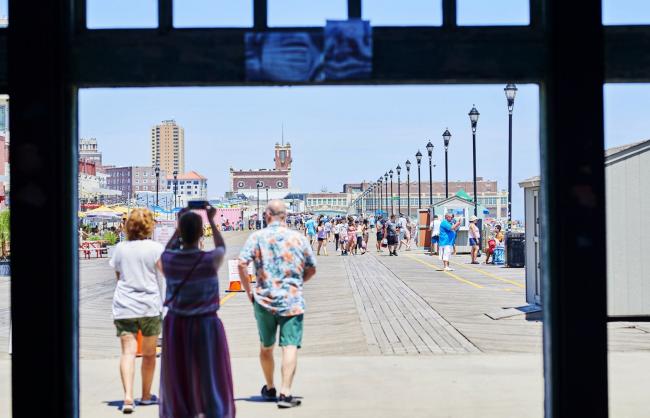 © Bloomberg. A person uses a smartphone to take a photograph of the boardwalk in Asbury Park, New Jersey on July 9. 