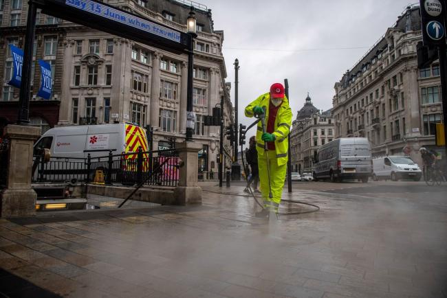 © Bloomberg. A Veolia Environnement SA worker cleans the pavement outside Oxford Circus underground station in London, U.K., on Thursday, June 11, 2020. The government said Tuesday that non-essential shops, which have been shut since March, can reopen Monday, so long as they can apply social distancing rules. Photographer: Chris J. Ratcliffe/Bloomberg