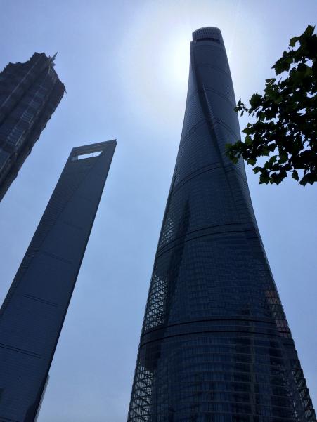 © Duncan Hewitt. The Shanghai Tower (right) silhouetted against the morning sun, with China's previous tallest buildings, the Shanghai World Financial Center, to its left, and the Jin Mao Tower (far left)