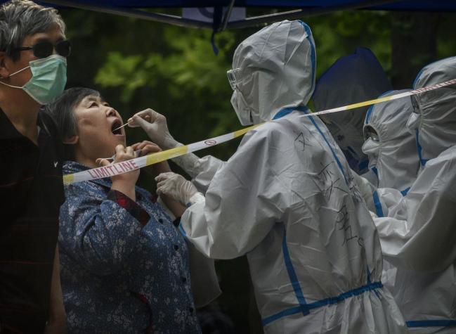 © Bloomberg. An epidemic control worker conducts a nucleic acid test for Covid-19 on a woman at a testing center in Beijing on June 20.