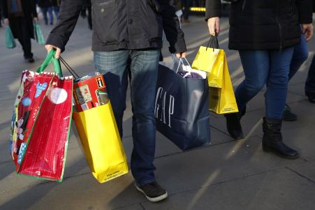 © Reuters/Luke MacGregor. Shoppers carry bags along Oxford street during the final weekend of shopping before Christmas in London, Dec. 20, 2014.