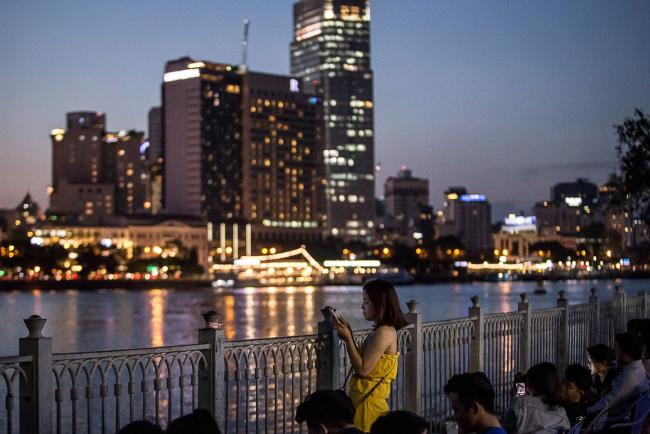 © Bloomberg. A woman uses a smartphone while standing along the Saigon River in Ho Chi Minh city, Vietnam, on Wednesday, Sept. 11, 2019. Vietnam, is the seventh-largest goods exporter to the U.S. Manufacturers are shifting production to places like Vietnam to avoid U.S. tariffs on Chinese imports — one of the more vivid examples of how trade wars are redirecting channels of goods and services. Photographer: Yen Duong/Bloomberg