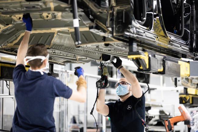 © Bloomberg. Workers wearing protective face masks affix parts to the underside of an automobile on the assembly line inside the Mercedes-Benz AG automobile plant, operated by Daimler AG, in Kecskemet, Hungary, on Thursday, May 7, 2020. Hungary’s monetary authority is sticking to its projection for a 2%-3% increase in gross domestic product even as the government, bank analysts and foreign institutions expect a deep contraction due to the coronavirus pandemic.