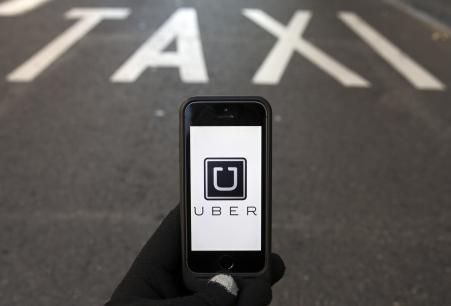 © Reuters/Sergio Perez. The logo of car-sharing service app Uber on a smartphone over a reserved lane for taxis in a street is seen in this photo illustration taken in Madrid on Dec. 10, 2014.