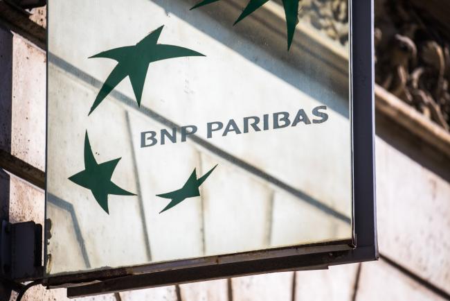© Bloomberg. A BNP Paribas SA logo sits on a sign outside a BNP Paribas bank branch in Paris, France, on Tuesday, July 18, 2017. BNP Paribas agreed to pay $246 million to settle Federal Reserve allegations that the bank failed to keep its currency traders from using electronic chatrooms to manipulate prices.