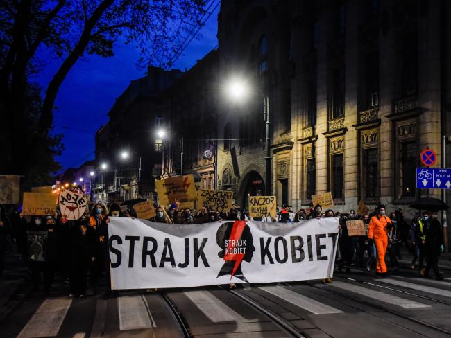 © Bloomberg. People hold a giant banner of Women's strike and shout slogans as they continue to protest against the Constitutional Court ruling on tightening the abortion law in Krakow on Nov. 1.