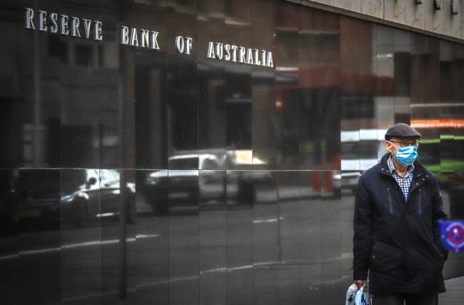 © Bloomberg. A pedestrian wearing a face mask walks past the Reserve Bank of Australia (RBA) building, during a partial lockdown imposed due to the coronavirus, in Sydney, Australia, on Monday, May 18, 2020. Australia’s central bank decided against buying government bonds last week, the first time that’s happened since it began a quantative easing program in late March that sought to hold down three-year yields in order to lower interest rates across the economy. Photographer: David Gray/Bloomberg