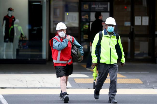 © Bloomberg. AUCKLAND, NEW ZEALAND - AUGUST 20: Pedestrians wearing protective face masks during Level 3 lockdown on August 20, 2020 in Auckland, New Zealand. COVID-19 restrictions have been reinstated across New Zealand as authorities work to contain a new COVID-19 outbreak in the community. Auckland is at Level 3 lockdown restrictions, while the rest of New Zealand is operating under Level 2. The restrictions will be in place until 11:59pm Wednesday 26 August, with Cabinet to review those settings on 21 August. COVID-19 restrictions were reintroduced across New Zealand on Wednesday 12 August in response to the discovery of a COVID-19 cluster in Auckland. (Photo by Hannah Peters/Getty Images) Photographer: Hannah Peters/Getty Images AsiaPac
