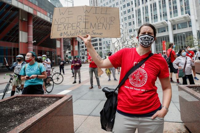 © Bloomberg. A protestor holds a sign during the Occupy City Hall Protest and Car Caravan hosted by Chicago Teachers Union in Chicago, Illinois, on August 3, 2020.  Photographer: Kamil Krzaczynski/AFP via Getty Images