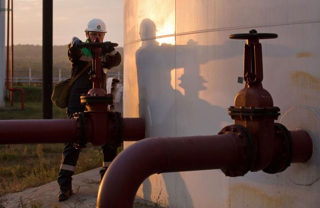 © Bloomberg. An employee turns a control valve on pipework beside a storage tank at an oil delivery point operated by Bashneft PAO in Sergeevka village, near Ufa, Russia, on Monday, Sept. 26, 2016. Bashneft distributes petroleum products and petrochemicals around the world and in Russia via filling stations. Photographer: Andrey Rudakov/Bloomberg