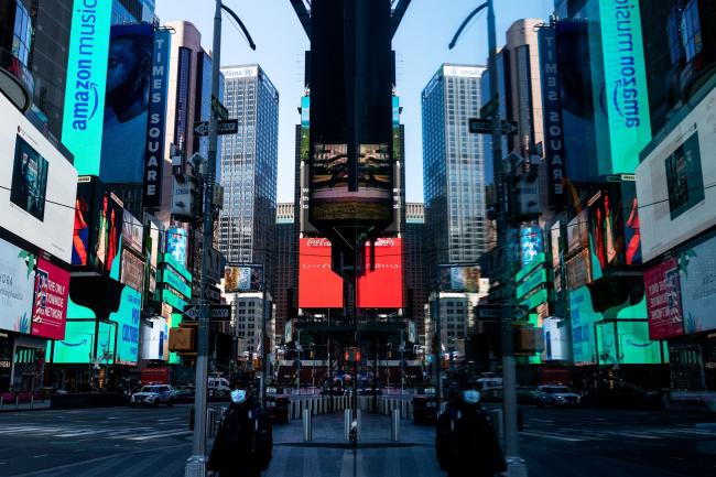 © Bloomberg. A pedestrian wearing a protective mask waits to cross a street in the Times Square area of New York on May 12.