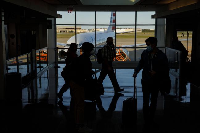 © Bloomberg. Passengers pass in front of an American Airlines Group Inc. airplane at Tulsa International Airport (TUL) in Tulsa, Oklahoma, U.S., on Thursday, Oct. 1, 2020. American Airlines Group Inc. and United Airlines Holdings Inc.will start laying off thousands of employees as scheduled, spurning Treasury Secretary Steven Mnuchin’s appeal for a delay as he negotiates with Congress over an economic relief plan that includes payroll support for U.S. carriers. Photographer: Patrick T. Fallon/Bloomberg
