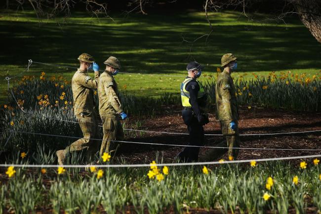 © Bloomberg. MELBOURNE, AUSTRALIA - AUGUST 04: Police and Australian Defence Force patrols are seen in the Fitzroy Gardens on August 04, 2020 in Melbourne, Australia. Retail stores across Melbourne will close to customers as further stage 4 lockdown restrictions are implemented in response to Victoria's ongoing COVID-19 outbreak. The new rules, which come into effect at 11:59 on Wednesday 5 August, will see the majority of retail businesses like clothing, furniture, electrical and department stores will be closed to the public for the duration of the stage 4 restrictions. Businesses will be able to operate click and collect services with social distancing and contactless payments. Supermarkets, grocery stores, bottle shops, pharmacies, petrol stations, banks, news agencies and post offices will remain open during the lockdown. Melbourne residents are subject to a curfew from 8pm to 5am, must stay within a 5km radius of their homes along with limits on hours of exercise, while all students will return to home learning and childcare centres will close. (Photo by Daniel Pockett/Getty Images)