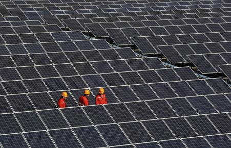 © Reuters. Workers walk among newly installed solar panels at a solar power plant in China's Zhejiang province. China led the surge in 2014 clean energy investments, pouring .5 billion into its solar and wind sectors last year, more than any other country.