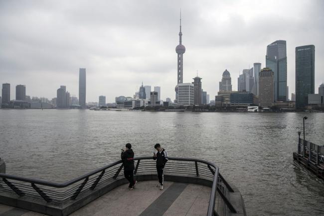 © Bloomberg. People stand on the Bund in Shanghai, China, on Friday, Feb. 12, 2021. Parts of northern China recently imposed lockdowns to curb coronavirus outbreaks and the government has taken steps to discourage millions of people from making their annual trips to their hometowns. That's likely to distort some of the traditional spending at this time of year. Photographer: Qilai Shen/Bloomberg