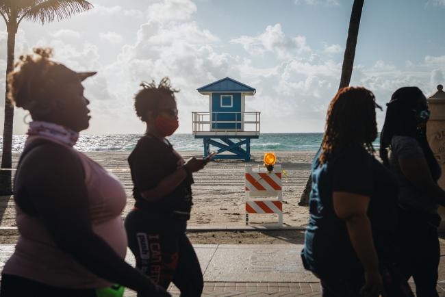 © Bloomberg. Pedestrians with and without protective masks walk on Hollywood Boardwalk in Hollywood, Florida, U.S., on Saturday May 23, 2020. Palm Beach County beaches reopened this week, ahead of the Memorial Day holiday, after Governor Ron DeSantis issued executive orders allowing certain businesses to reopen with restrictions. Photographer: Jayme Gershen/Bloomberg