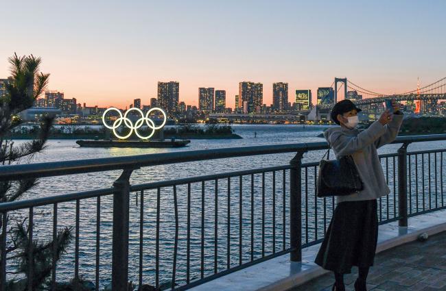 &copy Bloomberg. A person takes a photo of floating Olympic rings installed near Odaiba island, Tokyo on March 24. Photographer: Noriko Hayashi/Bloomberg
