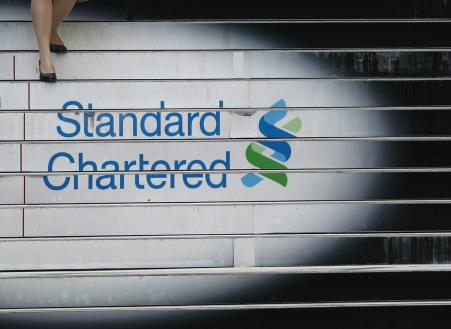 © Reuters/Bobby Yip. Standard Chartered reported a surprise loss for the third quarter on Tuesday. Pictured: A woman walks down the stairs of the Standard Chartered headquarters in Hong Kong, Oct. 13, 2010.