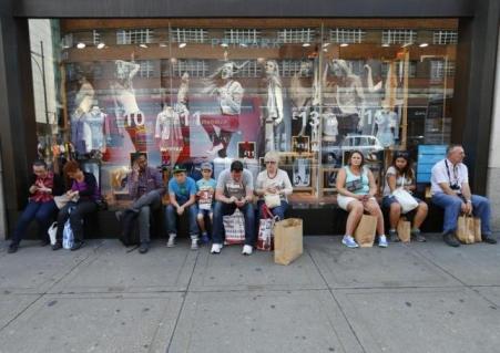 © Reuters/Andrew Winning. Shoppers sit with their bags on the window ledge of Primark on Oxford Street in London on Aug. 6, 2013.