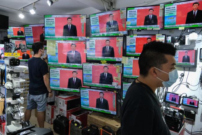 © Bloomberg. President Xi Jinping's speech in Shenzhen is broadcasted inside a store in Hong Kong, Oct. 14.