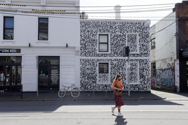 © Bloomberg. A pedestrian walks past a closed bar in Melbourne on Sept. 1.