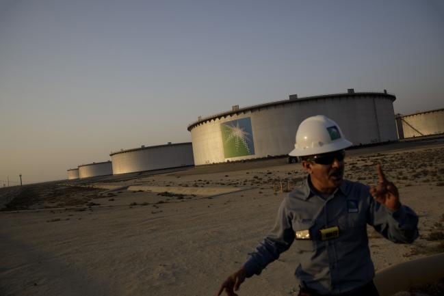 © Bloomberg. An employee walks past crude oil storage tanks at the Juaymah Tank Farm in Saudi Aramco's Ras Tanura oil refinery and oil terminal in Ras Tanura, Saudi Arabia, on Monday, Oct. 1, 2018. Saudi Arabia is seeking to transform its crude-dependent economy by developing new industries, and is pushing into petrochemicals as a way to earn more from its energy deposits. Photographer: Bloomberg/Bloomberg