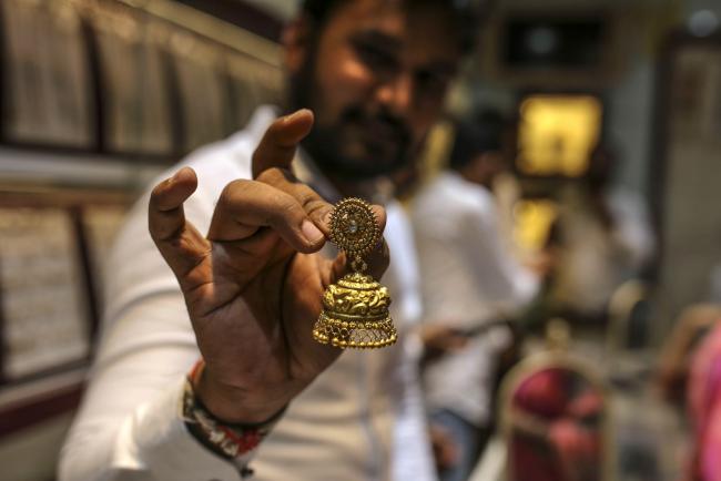 © Bloomberg. An employee holds a hold earring inside the Umedmal Tilokchand (U.T) Zaveri jewellery store during the festival of Dhanteras at the Zaveri Bazaar in Mumbai, India, on Friday, Nov. 13, 2020. India’s main holiday season -- culminating Saturday with Diwali, the festival of lights -- appears to be giving a much needed boost to demand, with online retail sales to business activity indicators signaling Asia’s third-largest economy is recovering.