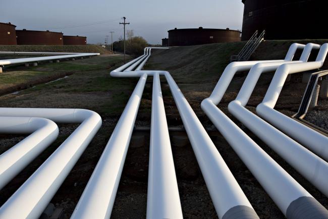 © Bloomberg. Pipelines run near oil storage tanks in Cushing, Oklahoma. Photographer: Daniel Acker/Bloomberg